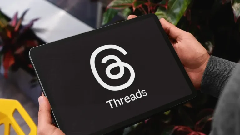 Person holding a tablet displaying the Threads app logo, social media platform for sharing updates.